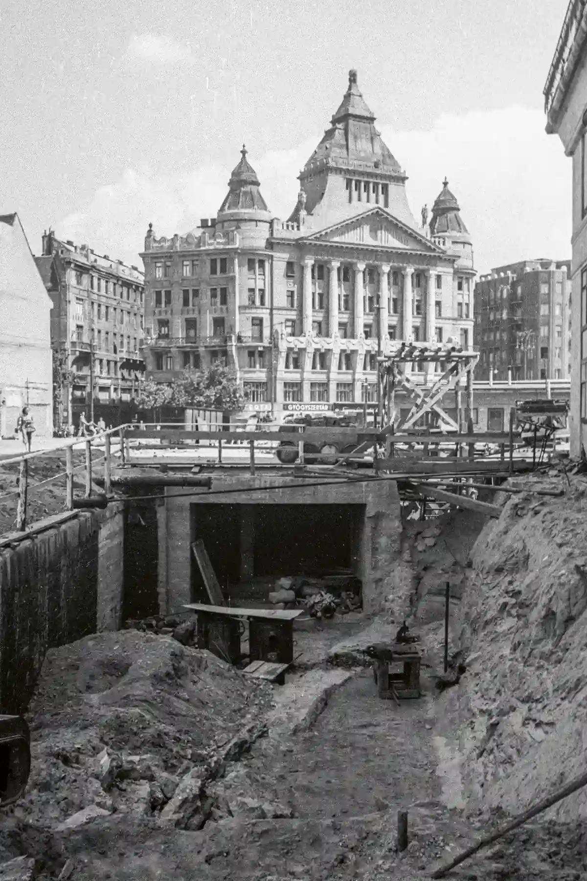 Deák Ferenc tér, a kisföldalatti új pályaszakaszának építése. Háttérben az Anker-palota, az egykori Kelet-Európai Biztosító Alpár Ignác által tervezett székháza. Később társasházzá alakították, híres lakói közé tartozott Békés Itala és Polónyi Gyöngyi színművész, valamint Hofi Géza előadóművész, humorista