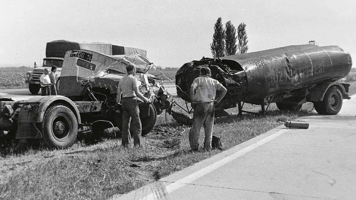 Baleset az M7-es autópályán (1977). A bitument szállító nyergesvontató a saját félpótkocsijával ütközött, miután utóbbi leszakadt és megpördült. A csípőre tett kézzel álló személy a gépkocsivezető, aki komolyabb sérülés nélkül szállt ki az összeroncsolódott fülkéből (fotó: Fortepan/Bojár Sándor)
