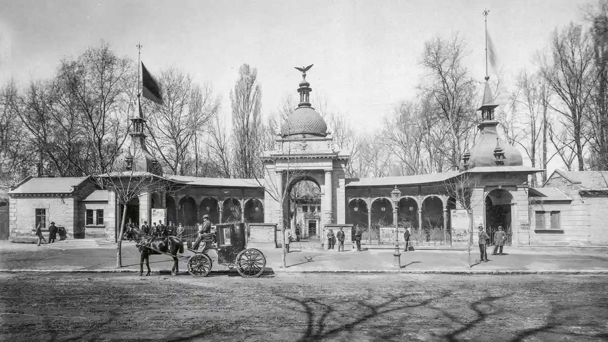 Állatkert, főbejárat, 1885 után. Az első, 1866-os kaput dokumentumok híján nem ismerjük, a mai elefántos pedig 1912-ben épült. A bejárat előtt konflis (egyfogatú könnyű bérkocsi) vár utasra